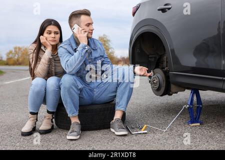 Ein junger Mann ruft beim Autoservice an. Reifenpanne Stockfoto