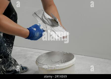 Professioneller Arbeiter, der im Innenbereich Putz auf Spachtelmesser legt, Nahaufnahme Stockfoto