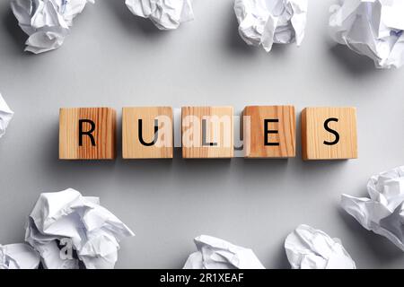 Wortregeln aus Holzwürfeln mit Buchstaben und zerknitterten Papierkugeln auf weißem Hintergrund, flach liegend Stockfoto