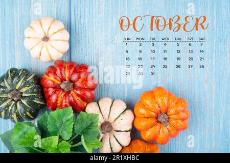 Oktober 2023 Kalender und Kürbisse auf holzfarbenem Hintergrund. Stockfoto