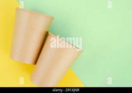 Umweltfreundliche Einwegbecher aus braunem Papier auf grünem Hintergrund. Stockfoto