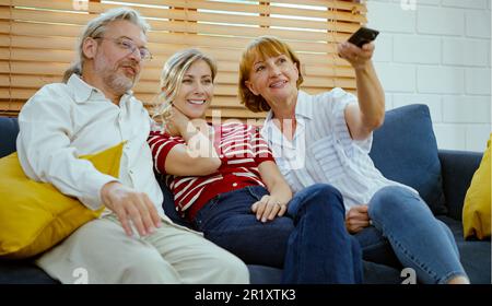 Glückliche Familie, die auf dem Sofa sitzt und zu Hause fernsieht. Stockfoto