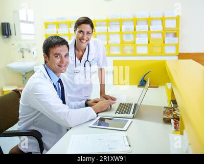 Ein technologieübergreifender Ansatz in der Forschung. Porträt eines gutaussehenden jungen Arztes und seiner Pflegehelferin mit einem Laptop. Stockfoto