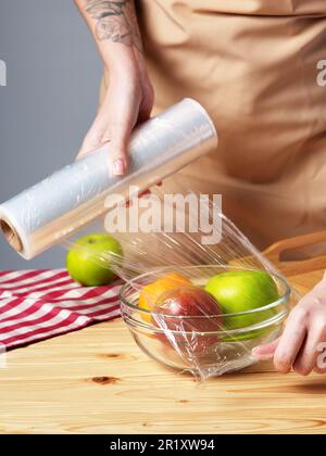 Eine Frau, die eine Schüssel frisches Obst auf einen Holztisch stellt Stockfoto