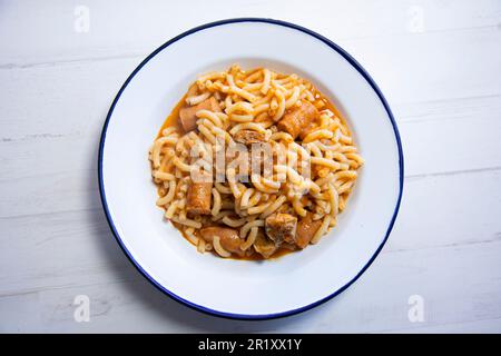 Paella fideua mit Schweinefleisch. fideuá ist ein Gericht aus Gandía, das auf ähnliche Weise wie Paella hergestellt wird, allerdings auf der Grundlage von Nudeln anstelle von Reis. Stockfoto