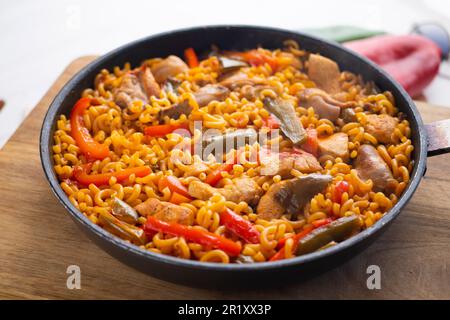 Paella fideua mit Huhn. Fideuá ist ein Gericht aus Gandía, das auf ähnliche Weise wie Paella hergestellt wird, allerdings auf Nudeln statt Reis basiert. Stockfoto