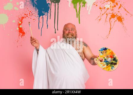 Fat man benimmt sich wie ein wichtiger Künstler mit Pinsel und Farbe in der Hand Stockfoto