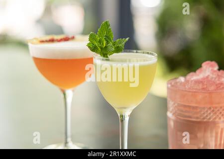 Verschiedene köstliche Sommercocktails auf einem grauen Tisch im Restaurant im Freien Stockfoto