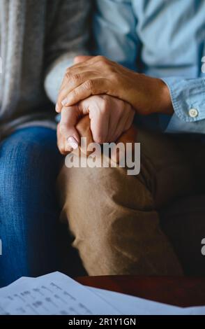 Händchenhalten, Seniorenpaar und Abschluss der Lebensversicherung mit Papierkram im Wohnzimmer. Zuhause, Sofa und ältere Menschen mit Einfühlungsvermögen, Hoffnung und Stockfoto