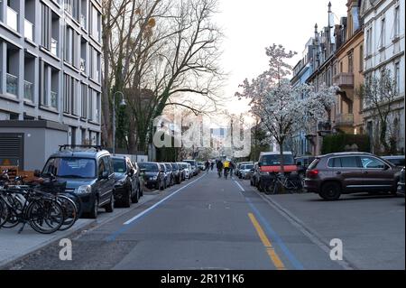 Eine Reihe von Autos parkt auf dem Bürgersteig entlang einer belebten Straße der Stadt Stockfoto