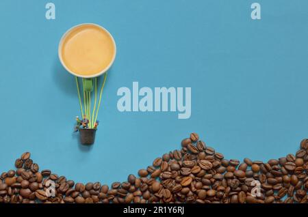 Abstrakter Heißluftballon aus Espresso Cup und Miniature People. Berge aus Kaffeebohnen Stockfoto