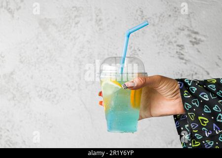 Eine Frau mit Seifenblasentee und Limonade vor einer grauen Steinwand Stockfoto