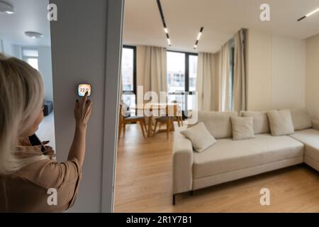Frau, die ein Smartphone verwendet, um die Schnittstelle für die Konnektivität zu Hause zu steuern. Stockfoto