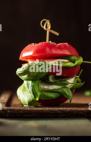 Ein köstliches Sandwich einer veganen Tomate mit Mozzarella und Basilikum auf einem Tablett Stockfoto