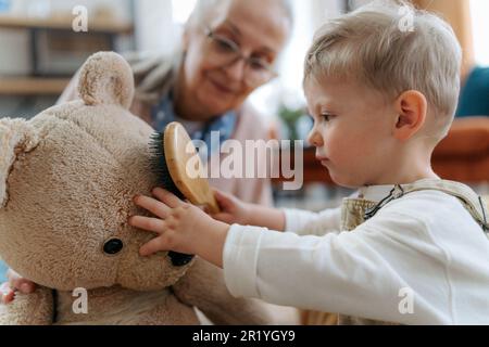 Der kleine Junge und die Großmutter kümmern sich um das Stofftier. Stockfoto