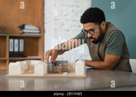 Ein junger multirassistischer Architekt, der ein Haus in seinem Büro entwirft. Stockfoto