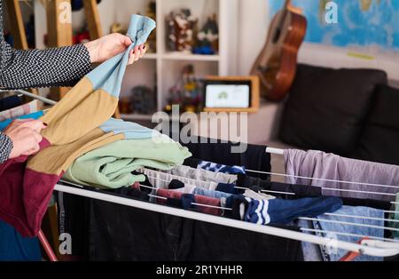 Berlin, Deutschland. 05. Mai 2023. Eine Mutter nimmt an einer Videokonferenz Teil, während sie die Wäsche im Zimmer ihres Kindes zusammenfaltet. Kredit: Annette Riedl/dpa/Alamy Live News Stockfoto