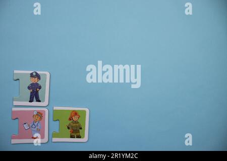 Informationspuzzles am Rand des blauen Hintergrunds. Polizist, Feuerwehrmann, Doktor Stockfoto