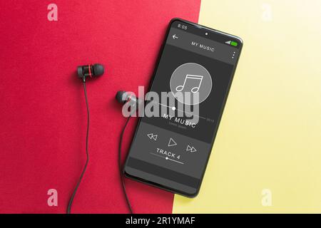 Musik-Player im Telefon, kabellose Kopfhörer und Telefon. Schwarze Kopfhörer und ein Musik-Player auf dem Bildschirm des Telefons. Speicherplatz kopieren Stockfoto