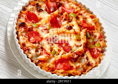 Nahaufnahme von Pizza Casserole mit zarter Penne Pasta, gebräuntem Rindfleisch, Peperoni, Oliven, Paprika, Und Käse mit Marinara-Sauce in Weiß Stockfoto