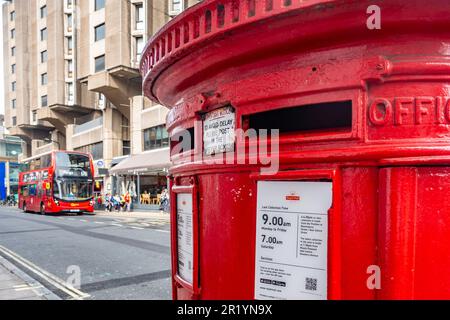 Ein rotes Postfach von Royal Mail im Vordergrund und ein roter Doppeldeckerbus im Hintergrund auf der Great Russel Street in London, Großbritannien Stockfoto