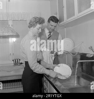 In der Küche 1950er. Ein junges Paar spült in der Küche ab, sie reinigt die Teller und er trocknet sie mit einem Handtuch. Er ist Sängerin Cacka Israelsson, 1929-2013. Schweden 1954. Conard Ref. 2643 Stockfoto