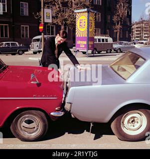 Fahren in der 1960er. Ein Mann steht bei zwei Autos, die entweder viel zu nah beieinander geparkt oder miteinander kollidiert sind. Der rote Opel Kadett steht so, dass die Stoßstange zum anderen Auto zeigt. Was der Mann mit seinem Gesichtsausdruck meint, ist schwer zu interpretieren, aber höchstwahrscheinlich besitzt er eines der Autos und ist natürlich nicht zufrieden mit dem, was er sieht. Schweden 1969 Kristoffersson Stockfoto