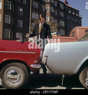 Fahren in der 1960er. Ein Mann steht bei zwei Autos, die entweder viel zu nah beieinander geparkt oder miteinander kollidiert sind. Der rote Opel Kadett steht so, dass die Stoßstange zum anderen Auto zeigt. Was der Mann mit seinem Gesichtsausdruck meint, ist schwer zu interpretieren, aber höchstwahrscheinlich besitzt er eines der Autos und ist natürlich nicht zufrieden mit dem, was er sieht. Schweden 1969 Kristoffersson Stockfoto