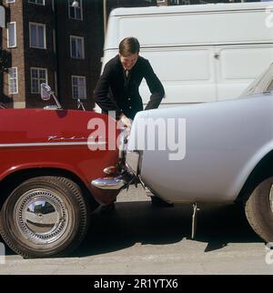 Fahren in der 1960er. Ein Mann steht bei zwei Autos, die entweder viel zu nah beieinander geparkt oder miteinander kollidiert sind. Der rote Opel Kadett steht so, dass die Stoßstange zum anderen Auto zeigt. Was der Mann mit seinem Gesichtsausdruck meint, ist schwer zu interpretieren, aber höchstwahrscheinlich besitzt er eines der Autos und ist natürlich nicht zufrieden mit dem, was er sieht. Schweden 1969 Kristoffersson Stockfoto