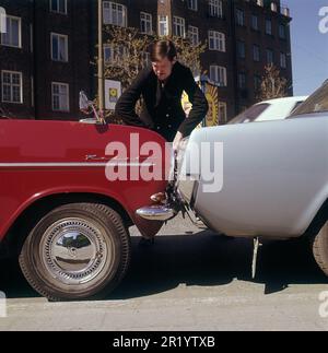 Fahren in der 1960er. Ein Mann steht bei zwei Autos, die entweder viel zu nah beieinander geparkt oder miteinander kollidiert sind. Der rote Opel Kadett steht so, dass die Stoßstange zum anderen Auto zeigt. Was der Mann mit seinem Gesichtsausdruck meint, ist schwer zu interpretieren, aber höchstwahrscheinlich besitzt er eines der Autos und ist natürlich nicht zufrieden mit dem, was er sieht. Schweden 1969 Kristoffersson Stockfoto