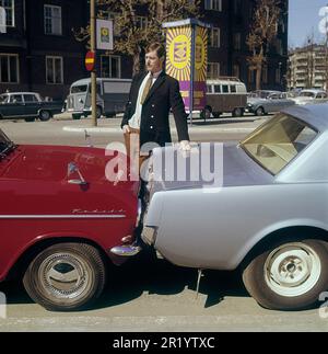 Fahren in der 1960er. Ein Mann steht bei zwei Autos, die entweder viel zu nah beieinander geparkt oder miteinander kollidiert sind. Der rote Opel Kadett steht so, dass die Stoßstange zum anderen Auto zeigt. Was der Mann mit seinem Gesichtsausdruck meint, ist schwer zu interpretieren, aber höchstwahrscheinlich besitzt er eines der Autos und ist natürlich nicht zufrieden mit dem, was er sieht. Schweden 1969 Kristoffersson Stockfoto