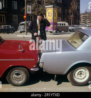 Fahren in der 1960er. Ein Mann steht bei zwei Autos, die entweder viel zu nah beieinander geparkt oder miteinander kollidiert sind. Der rote Opel Kadett steht so, dass die Stoßstange zum anderen Auto zeigt. Was der Mann mit seinem Gesichtsausdruck meint, ist schwer zu interpretieren, aber höchstwahrscheinlich besitzt er eines der Autos und ist natürlich nicht zufrieden mit dem, was er sieht. Schweden 1969 Kristoffersson Stockfoto