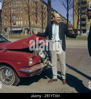 Fahren in der 1960er. Ein Mann steht vor seinem Auto, das bei einem Verkehrsunfall sichtbar beschädigt wurde. Ein Frontalaufprall oder jemand ist in sein Auto zurückgefahren. Er sieht frustriert aus. Schweden 1969 Kristoffersson Stockfoto