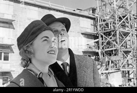 In den 1950er Jahren. Ein junges Paar auf einer Baustelle, wo neue Wohngebäude gebaut werden. Sie schauen nach oben, vielleicht auf ihre neue Wohnung, die bald einziehen wird. Schweden 1957. Stockfoto