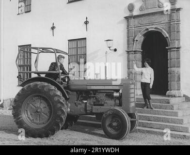 Landwirtschaft in den 1950er Jahren. Der neue BM-Volvo Traktor Bison wird als einer der weltweit größten Radtraktoren mit einem 4-Zylinder-Dieselmotor mit einer Motorleistung von ca. 70 ps vorgestellt und vorgestellt. Das Modell wurde zwischen den Jahren 1959 und 1966 hergestellt. Der Mann ist zur Eingangstür eines Residenzes gefahren, wo eine Frau steht und ihm zuwinkt. Schweden 1959 Stockfoto