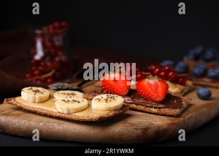 Frisches knuspriges Roggen-Knusperbrot mit verschiedenen Belägen auf schwarzem Tisch, Nahaufnahme Stockfoto