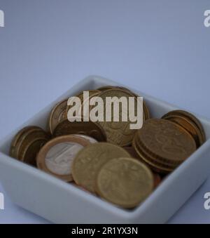 Nahaufnahme einer kleinen quadratischen Schüssel gefüllt mit Euro-Währungsmünzen Stockfoto