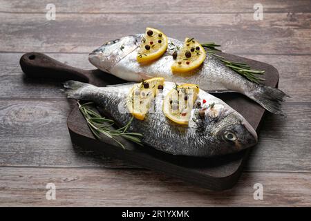 Frischer dorado-Fisch, Zitronenscheiben und Rosmarin-Zweige auf einem Holztisch Stockfoto