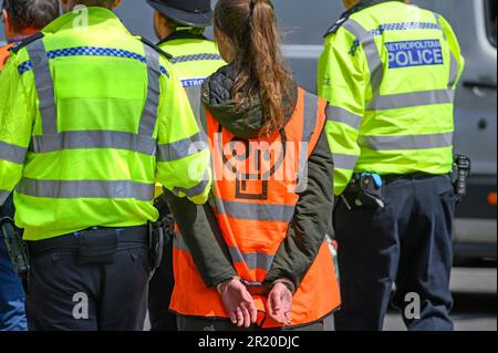 Junge Frau, die während eines Just Stop Oil-Protests am Parliament Square im Zentrum von London am 3. Mai 2023 in festen Handschellen festgenommen wurde. Stockfoto