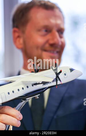 16. Mai 2023, Sachsen, Schkeuditz: Michael Kretschmer (CDU), sächsischer Ministerpräsident, steht nach der bahnbrechenden Zeremonie für die Produktionslinie des neuen Turboprop-Typs D328 Eco am Flughafen Leipzig/Halle hinter dem Modell eines D328 Eco. Flugzeughersteller Deutsche Aircraft plant hier den Bau eines nachhaltigen Regionalflugzeugs mit dem neuen Turboprop-Typ. Nach Angaben des Herstellers ist der D328 Eco eine nachhaltigere Entwicklung des Dornier 328, der Anfang der 1990er Jahre gebaut wurde, und es wird erwartet, dass das Werk bis zu 350 neue Arbeitsplätze schafft. Es wird in der Lage sein, 48 Flugzeuge pro Jahr in einem A zusammenzubauen Stockfoto