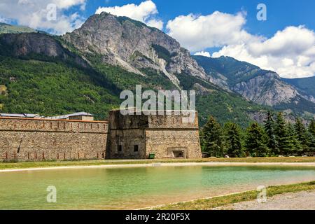 Blick auf den kleinen künstlichen See, die alte Militärfestung und die Berge im Hintergrund in Vinadio, Italien. Stockfoto