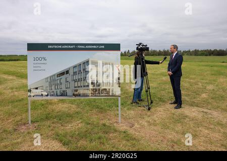 16. Mai 2023, Sachsen, Schkeuditz: Nico Neumann Vice President Operations Deutsche-Aircraft wird neben einem Panel der neuen Flugzeughalle am Flughafen Leipzig/Halle interviewt. Flugzeughersteller Deutsche Aircraft plant hier den Bau eines nachhaltigen Regionalflugzeugs mit dem neuen Turboprop-Typ. Nach Angaben des Herstellers ist der D328 Eco eine nachhaltigere Entwicklung des Dornier 328, der Anfang der 1990er Jahre gebaut wurde, und es wird erwartet, dass das Werk bis zu 350 neue Arbeitsplätze schafft. Es wird in der Lage sein, jährlich 48 Flugzeuge auf einer Fläche von etwa 62.000 Quadratmetern zu montieren. Das Flugzeug, das kann Stockfoto