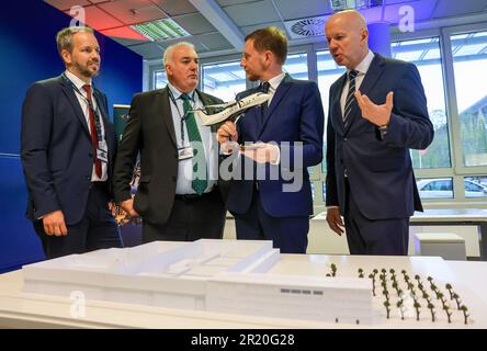 16. Mai 2023, Sachsen, Schkeuditz: Nico Neumann (l-r), Vice President Operations Deutsche Aircraft, Dave Jackson, Managing Director Deutsche Aircraft, Michael Kretschmer (CDU), Premierminister Sachsens, und Peter Gatz, Managing Director Private Wings, stehen am Modell eines D328 Eco und der neuen Produktionshalle am Flughafen Leipzig/Halle. Flugzeughersteller Deutsche Aircraft plant hier den Bau eines nachhaltigen Regionalflugzeugs mit dem neuen Turboprop-Typ. Nach Angaben des Herstellers ist der D328 Eco eine nachhaltigere Entwicklung des Dornier 328, der Anfang der 1990er Jahre gebaut wurde, und das Werk ist Ex Stockfoto