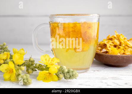 Kräutertee-Getränk aus Verbascum thapsus, der großen Königskerze, der Großen Königskerze oder der gemeinen Königskerze. Gelbe getrocknete Blütenblätter. Glasbecher. Stockfoto