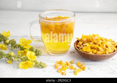 Kräutertee-Getränk aus Verbascum thapsus, der großen Königskerze, der Großen Königskerze oder der gemeinen Königskerze. Gelbe getrocknete Blütenblätter. Glasbecher. Stockfoto