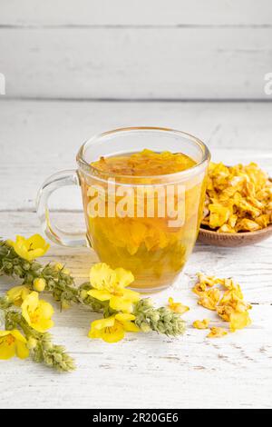 Kräutertee-Getränk aus Verbascum thapsus, der großen Königskerze, der Großen Königskerze oder der gemeinen Königskerze. Gelbe getrocknete Blütenblätter. Glasbecher. Stockfoto