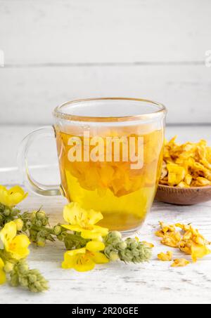 Kräutertee-Getränk aus Verbascum thapsus, der großen Königskerze, der Großen Königskerze oder der gemeinen Königskerze. Gelbe getrocknete Blütenblätter. Glasbecher. Stockfoto