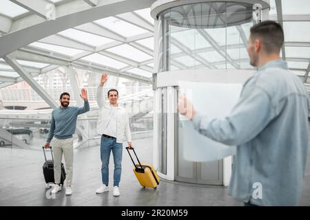 Touristen Männer Winken, Um Guy Am Flughafen Zu Treffen Und Zu Begrüßen Stockfoto