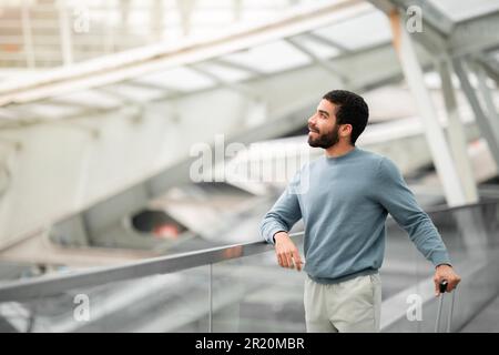 Arabischer Geschäftsmann Steht Mit Reisekoffer Und Blickt Auf Den Flughafen Stockfoto