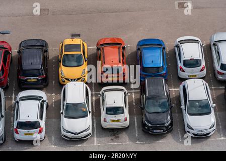 Autos auf einem Parkplatz geparkt, von oben gesehen. Markierte Parkbuchten, alle von einem geparkten Auto. Voll ausgestattete Parkboxen Stockfoto